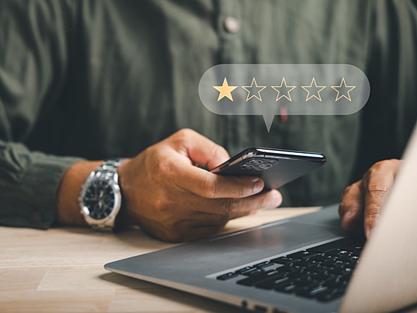 man using a phone and laptop with a graphic floating above showing one out of five stars